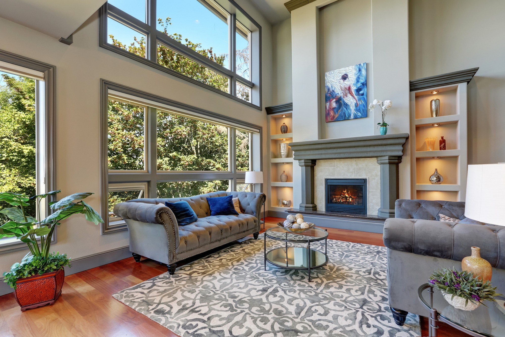 Grey interior of high vaulted ceiling family room in luxury house with fireplace and large windows. Northwest, USA.